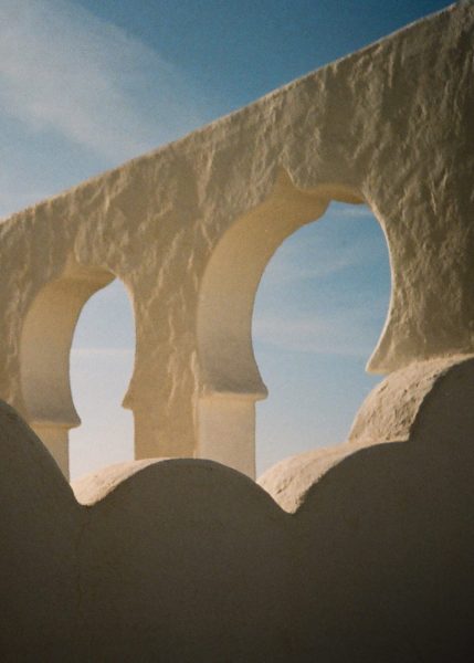 Sunlit traditional arched architecture against a clear blue sky, perfect for wedding photobooth backgrounds.