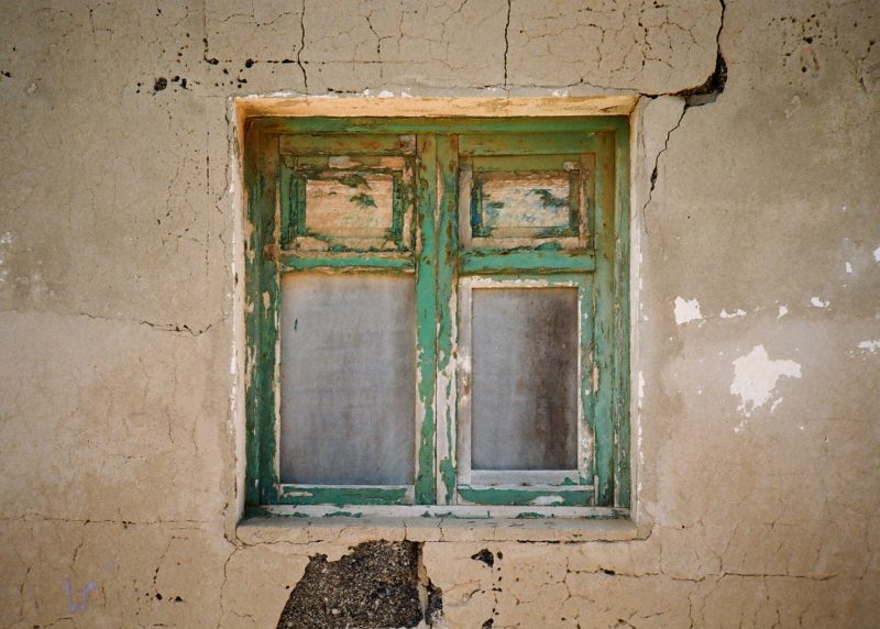 An old weathered green window frame, transformed into a magic mirror photobooth, on a cracked and textured wall.