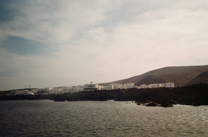 Coastal town with white buildings against a backdrop of rolling hills, featuring a free photobooth.