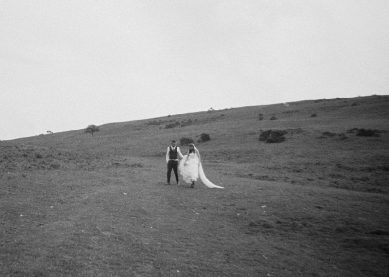 A bride and groom walking through an open field towards a magical photobooth.