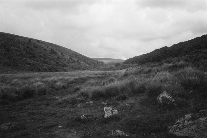 Grassy valley with overcast skies in a monochrome landscape, featuring a FREE magic mirror photobooth.