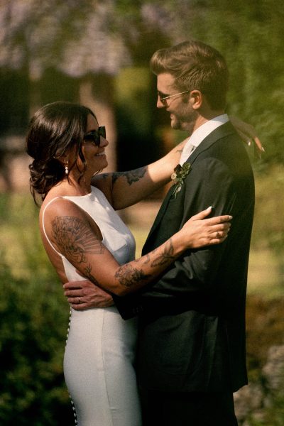 A couple embraces tenderly in their wedding attire, bathed in the warm glow of sunlight.