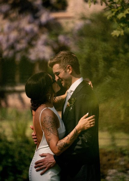 A couple embracing and about to kiss, surrounded by nature.