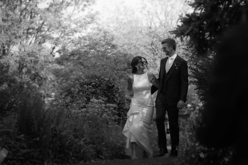Couple in formal attire walking together in a garden.