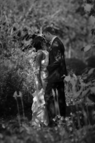 A couple in wedding attire sharing an intimate moment in a dimly lit garden setting.