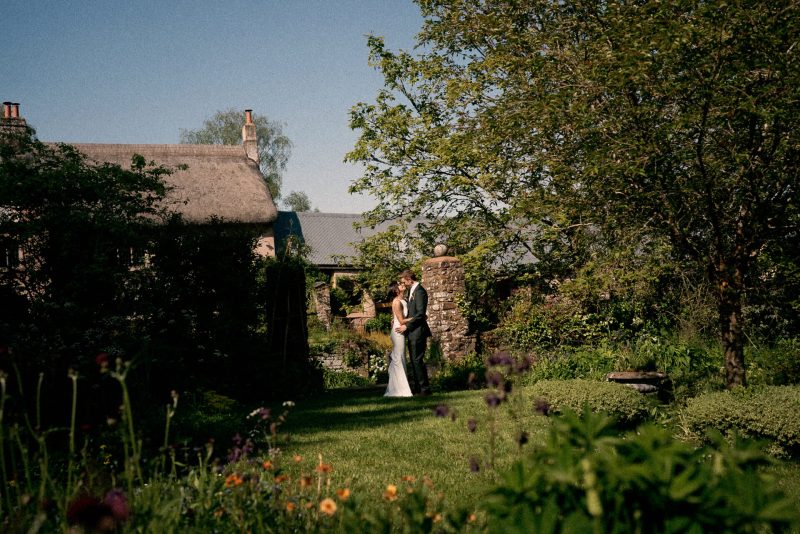A couple in wedding attire sharing a private moment in a lush garden.